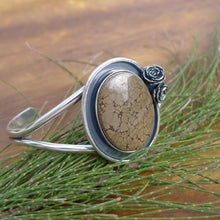 Load image into Gallery viewer, Chunky Nature inspired authentic turquoise cuff bracelet with small flowers on a wood table with pine needles