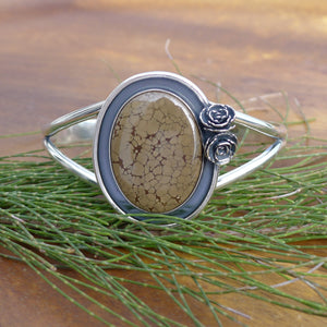 Chunky Nature inspired authentic turquoise cuff bracelet with small flowers on a wood table with pine needles