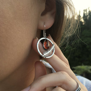 Nature inspired fern earrings hoop of silver with teardrop of amber and a fern accent earrings worn by a woman