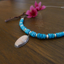 Load image into Gallery viewer, Vintage pink coral pendant hangs from turquoise bead and handmade silver bead necklace on wood background turquoise bead necklace